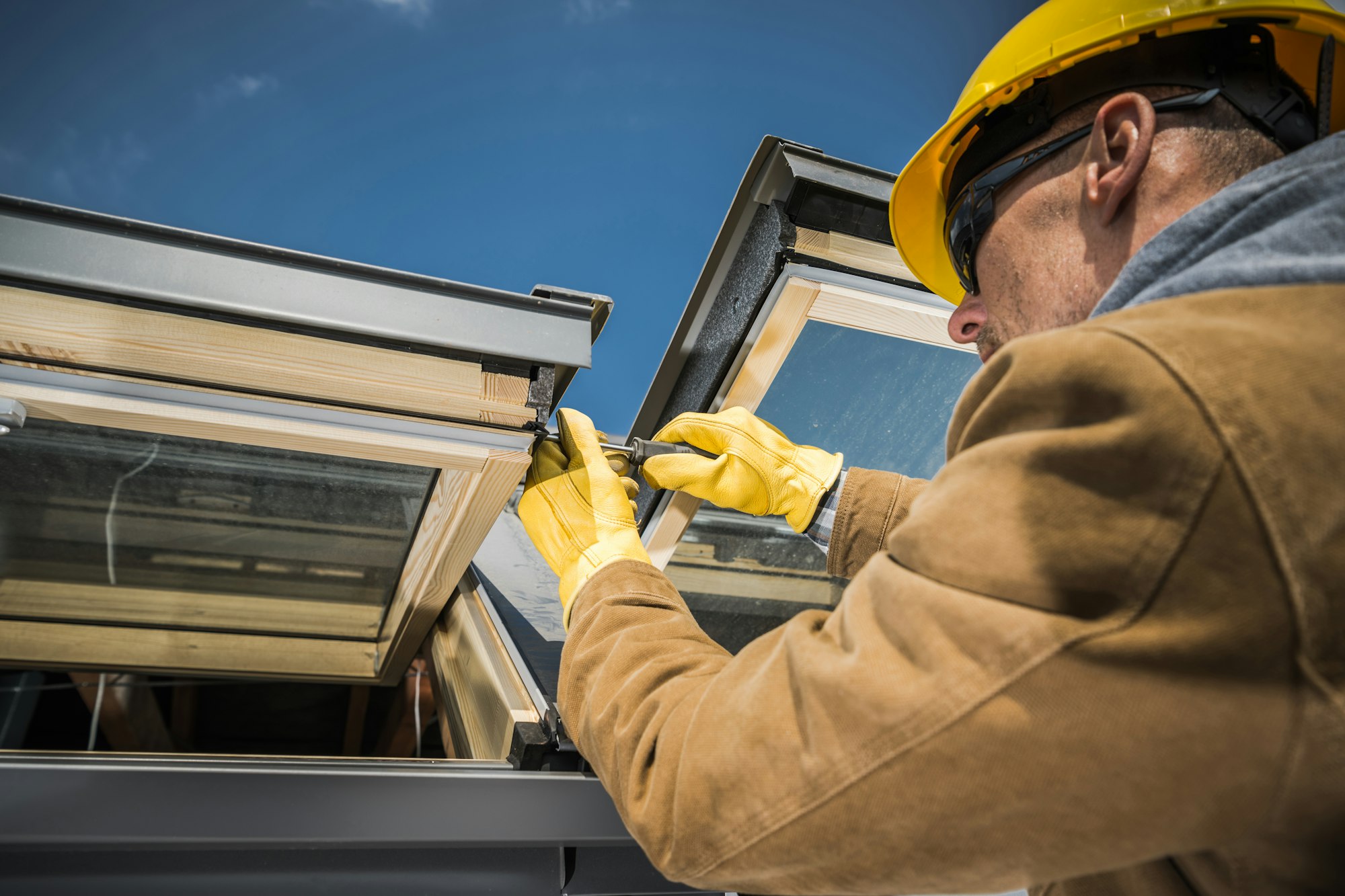 Handwerker befestigt die äußere Abdeckung eines Holz-Dachfensters