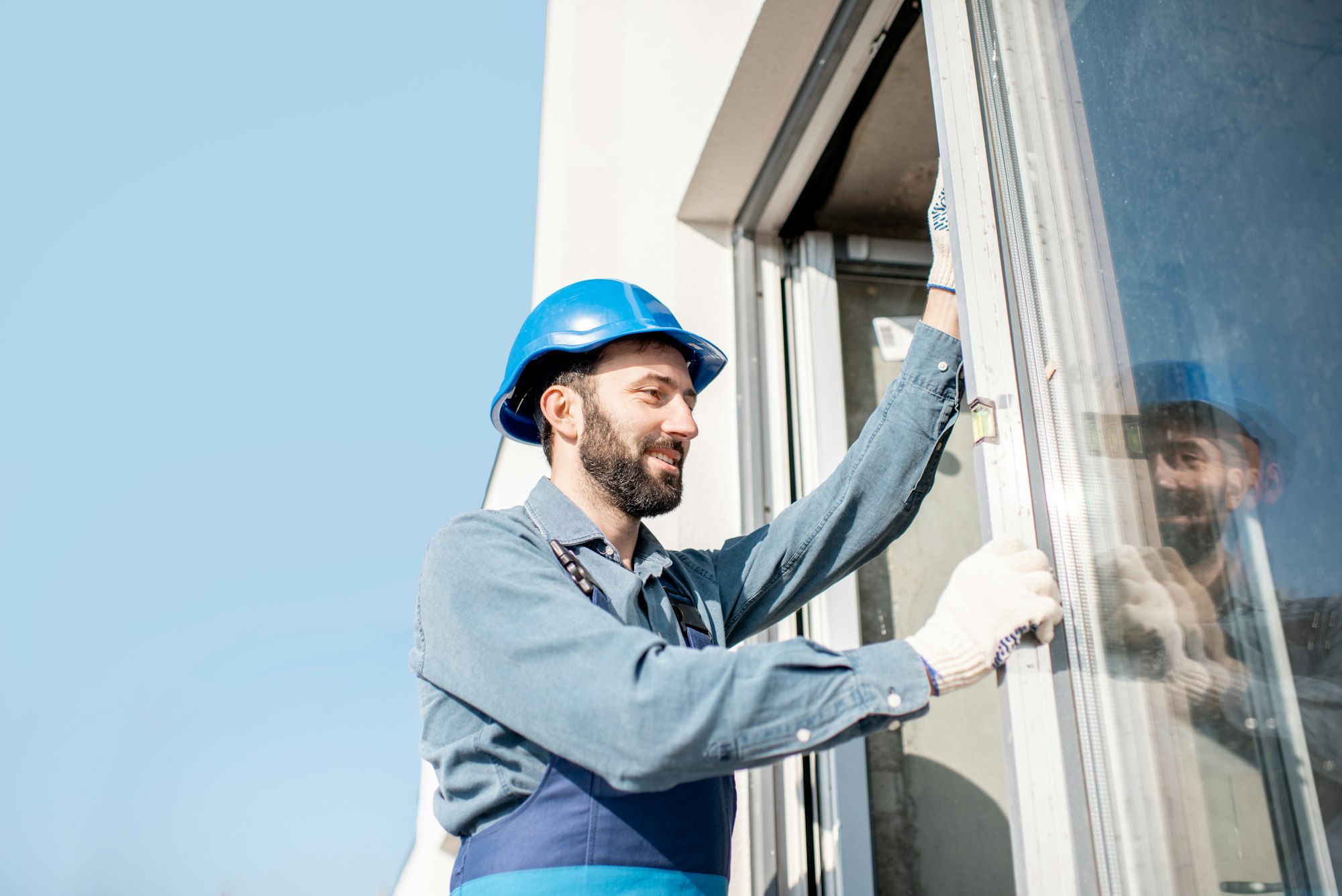 Monteur arbeitet von außen am Rahmen eines geöffneten Fensters