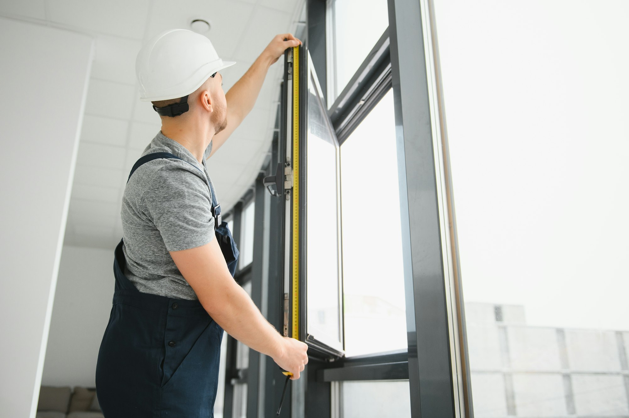 service man installing window with screwdriver